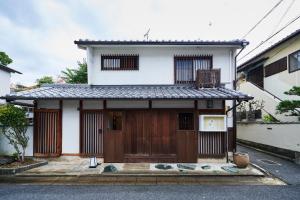 une petite maison blanche avec une porte en bois dans l'établissement Kohaku, à Nara