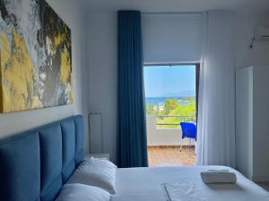 een slaapkamer met een bed met een blauw hoofdeinde en een raam bij Dine Apartments in Ksamil