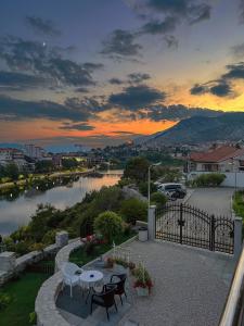 una puesta de sol sobre un río con una mesa y sillas en Apartmani HM, en Trebinje