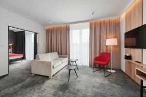 sala de estar con sofá y silla roja en Best Western Plus Hotel Rzeszow City Center en Rzeszów