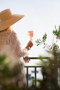 una mujer con un sombrero de paja sosteniendo una copa de vino en Hotel California by Aycon en Sveti Stefan