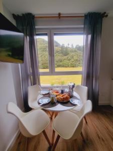 Maile Apartamentos في بوت: طاولة عليها طبق من الطعام أمام النافذة