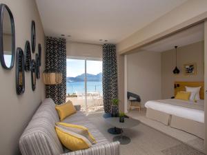 a living room with a couch and a bed and a window at Hôtel La Caravelle in Calvi