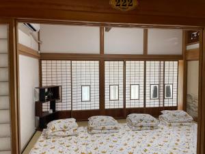 1 dormitorio con 2 camas y ventana grande en 旭日山荘 