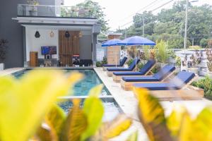 une piscine avec des chaises longues et des parasols dans un bâtiment dans l'établissement Paradise Bay Hotel Boutique, à Herradura