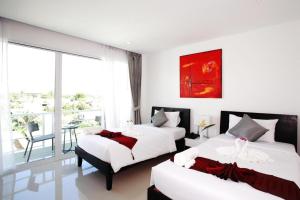 a bedroom with two beds and a table with a chair at One World One Home Naiharn Hotel in Rawai Beach