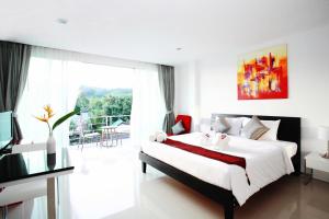 a bedroom with a bed and a large window at One World One Home Naiharn Hotel in Rawai Beach