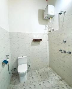 a white bathroom with a toilet and a shower at Bardia Eco Friendly Homestay in Bhurkīā