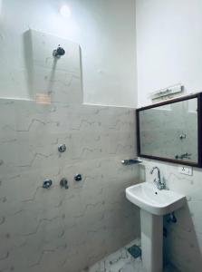 a white bathroom with a sink and a mirror at Bardia Eco Friendly Homestay in Bhurkīā