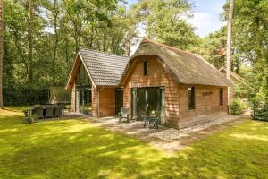 a small wooden cabin with a grass yard at Luxe, sfeervol en vrijstaand boshuis Chalet LaMast in Norg