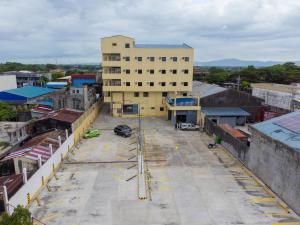 un aparcamiento vacío frente a un edificio en Sundaze Dormitel en Naga