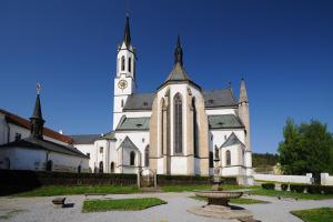 eine große weiße Kirche mit einem Uhrturm in der Unterkunft Hotel Šumava in Vyšší Brod