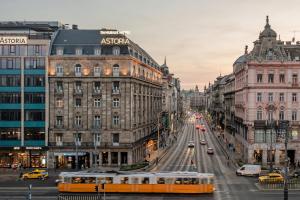 een gele bus die door een straat met gebouwen rijdt bij Danubius Hotel Astoria City Center in Boedapest