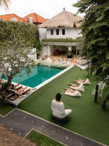 un grupo de personas sentadas en la hierba junto a una piscina en Puri Garden Hotel & Hostel en Ubud