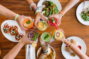 un grupo de personas sosteniendo bebidas en una mesa con comida en Puri Garden Hotel & Hostel en Ubud