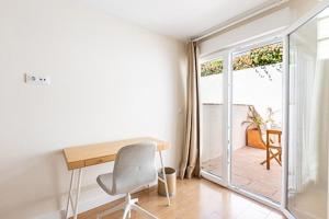 escritorio y silla en una habitación con puerta corredera de cristal en Oasis Urbano Ciudad Expo en Mairena del Aljarafe