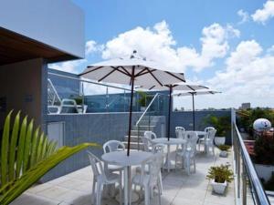 a patio with tables and chairs and an umbrella at Hotel Agua Marinha in Natal