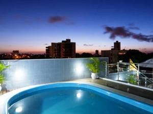 a swimming pool on top of a balcony with a city skyline at Hotel Agua Marinha in Natal