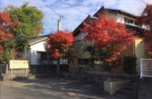 une maison avec des arbres rouges devant elle dans l'établissement 一客一亭の宿 遊楽, à Satsumasendai