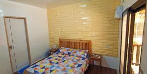 a small bedroom with a bed with a colorful comforter at CocoHut Beach House in Locaroc