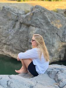 Eine Frau, die auf einem Felsen in der Nähe des Wassers sitzt. in der Unterkunft Wadi Al Arbeieen Resort in Muscat