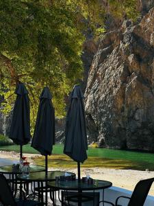 eine Gruppe von Tischen mit Sonnenschirmen auf einer Terrasse in der Unterkunft Wadi Al Arbeieen Resort in Muscat