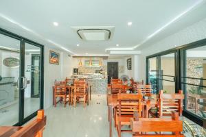 un restaurant avec des tables et des chaises en bois et un comptoir dans l'établissement Porpiang Hotel - โรงแรมพอเพียง, à Nakhon Phanom