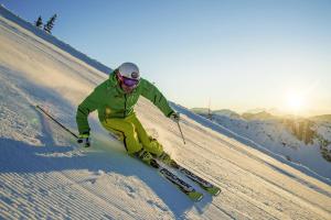 un hombre está esquiando por una pista cubierta de nieve en Hotel Krvavec, en Cerklje na Gorenjskem