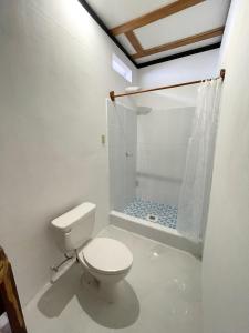 a white bathroom with a toilet and a shower at Mayan Spirit in Flores