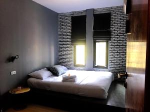 łóżko w pokoju z ceglaną ścianą w obiekcie La Malila Hostel w mieście Udon Thani