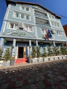 un edificio blu con una bandiera davanti di Hotel Heimli a Pristina