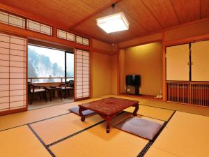 een Japanse kamer met een tafel en een televisie bij Yunohirakan in Takayama