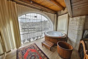 Habitación con bañera y ventana grande. en Divan Cave House en Göreme