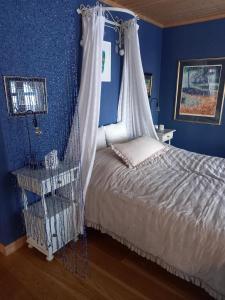 1 dormitorio azul con 1 cama con dosel en Villa Rørvik, en Svelvik