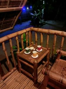 un banco de madera con dos tazas y platillos. en Balai Ko Beach & Cottages en El Nido