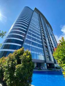 a tall building with a pool in front of it at AEON SUITES STAYCATION managed by ARIA HOTEL in Davao City