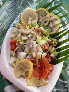 un plato de comida con verduras y rodajas de limón en Balai Ko Beach & Cottages en El Nido