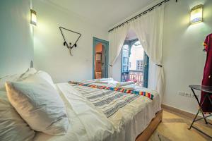 a bedroom with a bed with white sheets and a window at Riad Azawan in Marrakesh