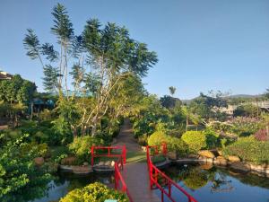 un ponte rosso sopra un laghetto in un giardino di K'Ho Cil Homestay Tà Nung a Da Lat