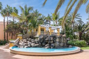 una casa con una fuente frente a una casa en Palm Oasis Maspalomas en Maspalomas