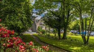 un chemin à travers un parc planté d'arbres et de fleurs dans l'établissement Pinehurst Lodge Hotel - Aberdeen, à Dyce