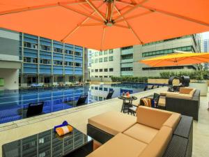an outdoor patio with a pool and orange umbrellas at The Mini Suites Eton Tower Makati in Manila