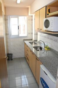 uma pequena cozinha com um lavatório e um micro-ondas em Le Batiment Apartmentos em Buenos Aires