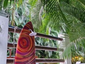 een kleurrijke surfplank op een paal naast een palmboom bij Dreamcatcher Hotel - Atrapasueños in Santa Teresa Beach