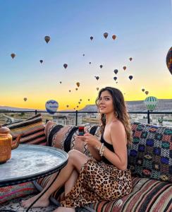 una mujer sentada en un sofá viendo globos de aire caliente en Garden Suites Hotel Cappadocia en Goreme