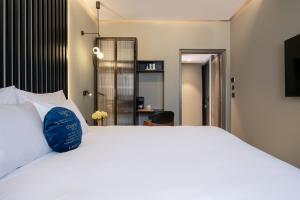 a bedroom with a large white bed with a blue pillow at Hotel Poli Urban By AFI Hotels in Tel Aviv