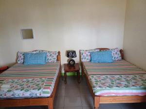 a room with two beds and a table with a clock at Calitang Pearl Cottage in Nacpan