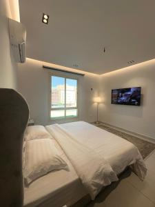 a bedroom with a large bed with a tv on the wall at اطلالة الريان شقة خاصة in Jeddah