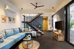 a living room with a blue couch and a tv at The Hanging Villa - A Luxury Pool Villa in Jaipur in Jaipur