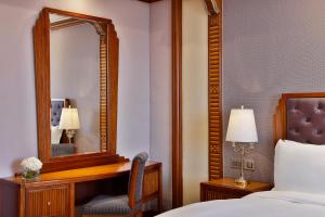 een slaapkamer met een spiegel, een bed en een stoel bij The Ritz-Carlton Jeddah in Jeddah